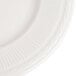 A close-up of a 10 1/4" ivory china plate with an embossed rim.