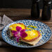 An Arcoroc Candour Azure porcelain brunch plate with food and a flower on it.