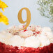 A white cake with a gold glitter number nine on top.