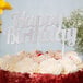 A cake with a silver glitter "Happy Birthday" sign on top.