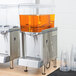 A white Crathco beverage dispenser bowl assembly with an orange container.