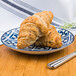 An Arcoroc Candour Azure porcelain B&B plate with two croissants on it.