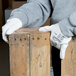A pair of white HPPE and synthetic fiber gloves with a white polyurethane palm coating being worn by a person handling wooden boards.
