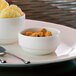 A white Villeroy & Boch porcelain ramekin with food on a plate and a spoon.