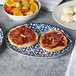 An Arcoroc Candour Azure oval platter with a bagel, jam, and fruit on it.