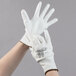 A pair of large hands wearing white Cordova warehouse gloves with white polyurethane palms.