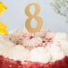 A frosted cake with a gold glitter number eight on top.