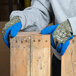 A person wearing Cordova blue latex palm coated gloves holding a piece of wood.