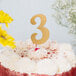 A white cake with a gold glitter number 3 on top.