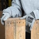 A person wearing Cordova Monarch gray engineered fiber cut resistant gloves holding a piece of wood.
