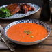 An Arcoroc Candour Azure deep soup bowl filled with soup on a table next to a plate of meat.
