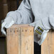 A person wearing Cordova Monarch gray work gloves with split leather palms leaning on a piece of wood.