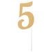 A gold glittery number 5 cake topper on a white stick.