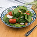 An Arcoroc Candour Azure porcelain salad plate with a spinach salad with tomatoes and vegetables.