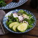 A close up of an Arcoroc Candour Azure porcelain salad plate with a salad of cucumbers and onions.