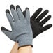 A pair of hands wearing Cordova warehouse gloves with gray and black palms.