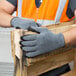 A person wearing Cordova gray grip gloves holding a piece of wood.