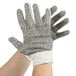 A hand wearing a Cordova work glove with white fabric and black PVC dots.