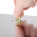A hand uses a key to screw a small metal nut onto a metal object.