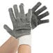 A person wearing Cordova gray work gloves with black PVC dots on the palm.