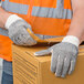 A person wearing Cordova work gloves with black PVC dots on a box.