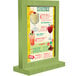 A Menu Solutions lime wood table tent with a glass display on a table in a cocktail bar.