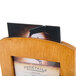 A Menu Solutions country oak wood framed table tent holding a menu on a table.