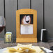 A Menu Solutions country oak wood menu tent on a table.
