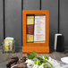 A Menu Solutions mandarin wood menu tent on a table.