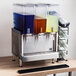 A Crathco Simplicity Bubbler refrigerated beverage dispenser with three different colored liquids.