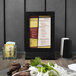 A Menu Solutions black framed wood menu tent on a table.
