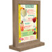 A Menu Solutions weathered walnut wood menu tent on a table with drinks.