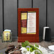 A Menu Solutions mahogany wood framed menu tent on a table.