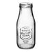 An Acopa glass milk bottle with a lid.