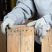 A person wearing Cordova gray gloves holding a piece of wood.