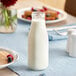 An Acopa glass milk bottle on a table.