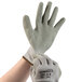 A hand wearing a pair of Cordova Cor-Grip II gray warehouse gloves with a white glove on top.