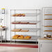 A Regency chrome slanted wire shelf with bakery pastries on display.