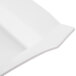 A close-up of a bright white square soup plate with curved edges.