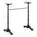 A black self-stabilizing cast iron bar height table base with two ornate legs and a connecting support bar.