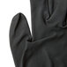 A close up of a Cordova Cor-Touch black foam nitrile glove with a thumb on a white background.