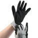 A pair of hands wearing black and gray Cordova Cor-Touch foam gloves.