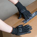 A person wearing Cordova black nylon gloves with black polyurethane palm coating opening a box.