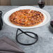 A white ceramic pizza serving tray with a pizza on it.