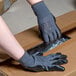 A person wearing Cordova gray and black gloves and putting on a box.