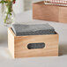A Choice natural wooden display crate with a stack of napkins in it.