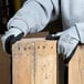 A person wearing Cordova gray nylon gloves with black foam nitrile palms holding wood.