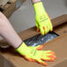 A person wearing Cordova yellow warehouse gloves with orange palms opening a box.