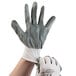 A hand wearing a Cordova white nylon glove with grey nitrile coating.