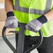 A man in a safety vest and Cordova striped canvas gloves holds a metal frame.